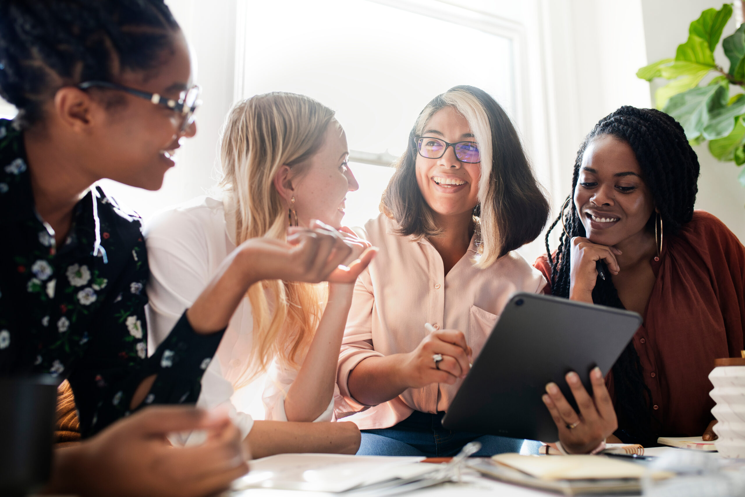 Four women having a meeting using a digital tablet